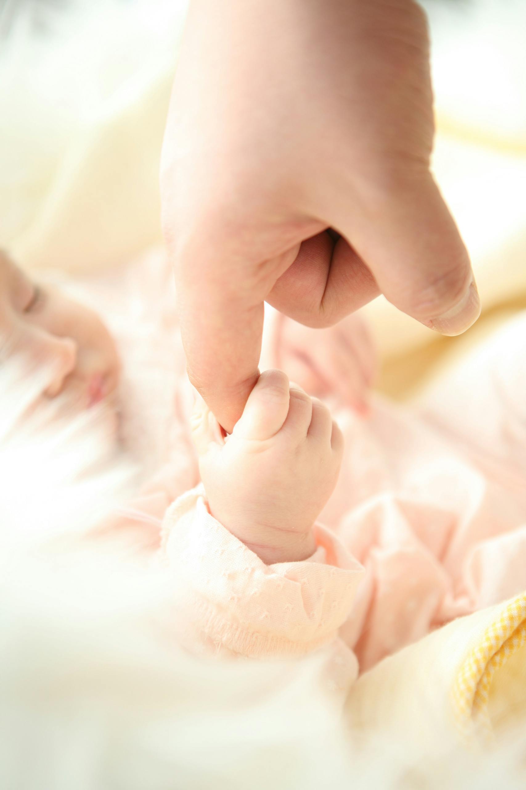 bébé tenant le doigt de sa maman avec la pince pouce-index