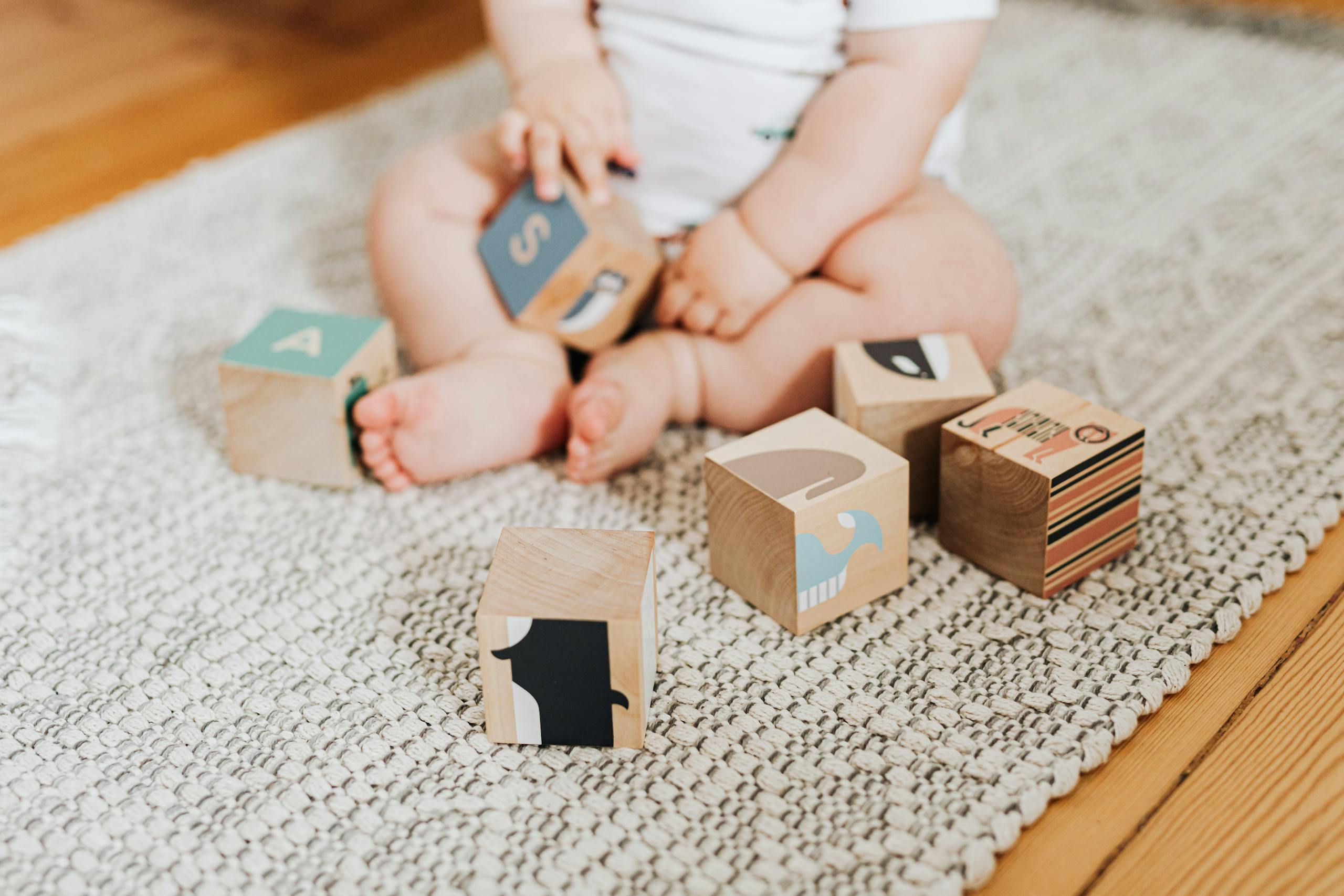 bébé-assis-joue-avec-des-jeux-d'éveil-cube-en-bois