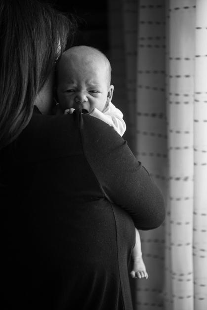 Mère tenant un bébé qui tousse doucement, illustrant le lien entre bébé et toux.