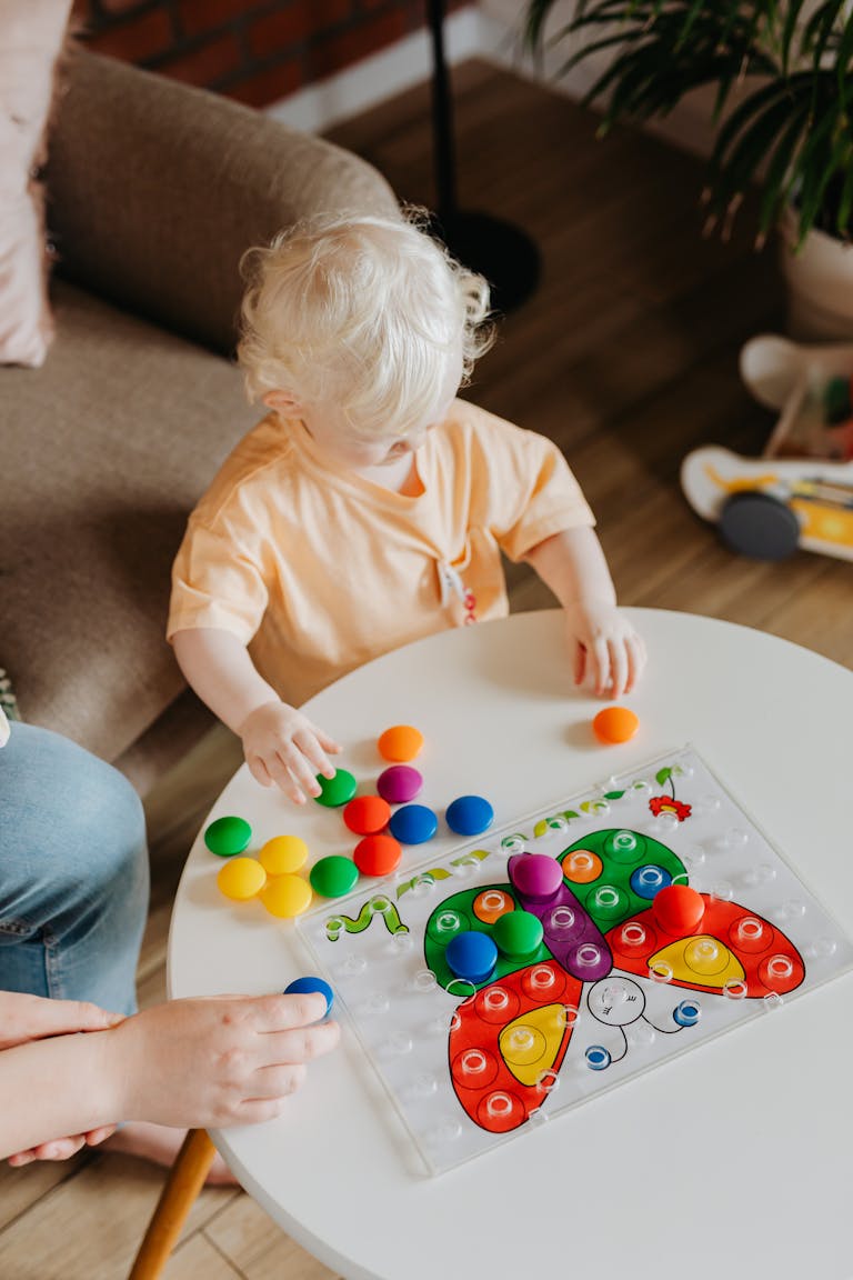 bébé-joue-sur-une-table-avec-des-jeux-d'éveil-en-forme-de-papillon-coloré