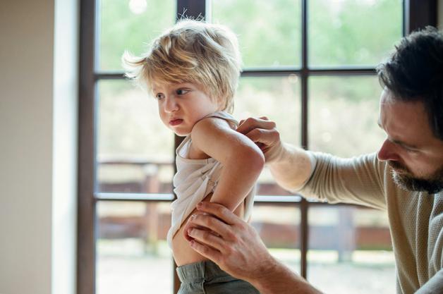 Un parent examine les lésions d'eczéma sur le bras d'un bébé, mettant en lumière les besoins de soins adaptés.