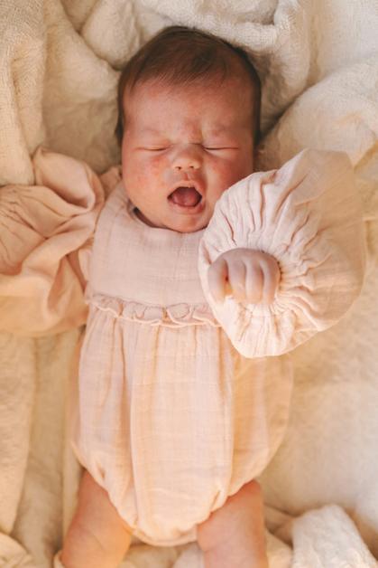 Un bébé endormi, vêtu d'une combinaison rose, symbolisant la douceur et l'innocence liée à la roseole.