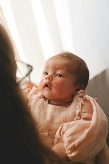 Bébé avec des joues roses observant attentivement, une image évoquant la roseole et son impact sur les jeunes enfants.