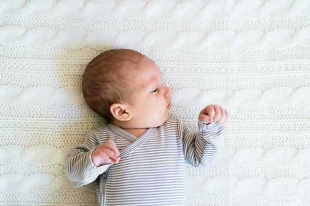 Bébé allongé sur un matelas, se demandant à quel âge un bébé se retourne pour explorer son environnement.