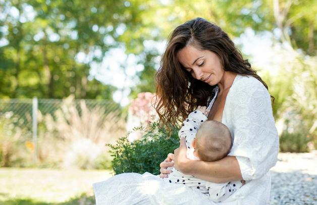 Allaitement mal de dos : Mère allaitant son bébé en pleine nature, l'allaitement peut entraîner un mal de dos si la posture n'est pas optimale.