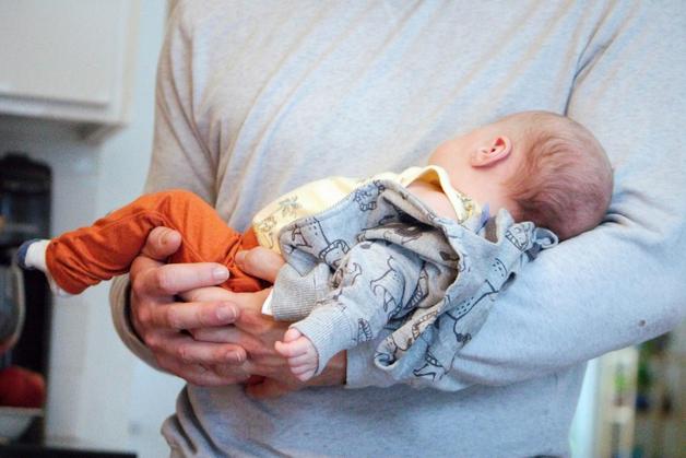 Un parent berce tendrement un bébé endormi dans ses bras, créant un moment doux et réconfortant.