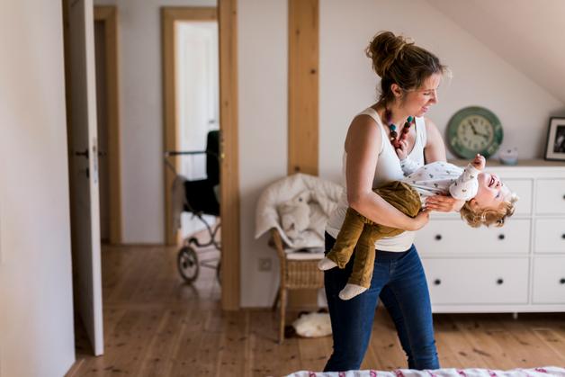 Maman berce tendrement son enfant dans une chambre lumineuse, créant un moment de complicité.