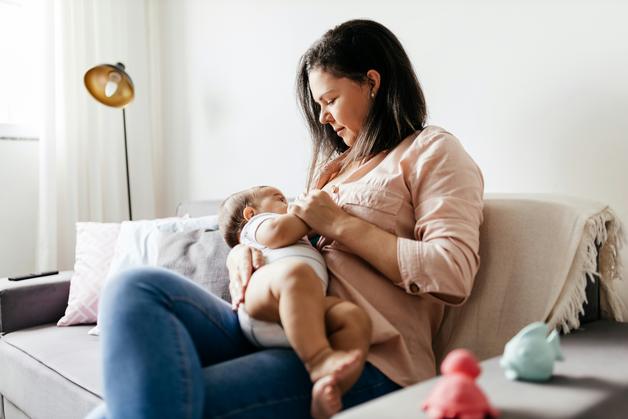 Maman allaitant son bébé sur un canapé, illustrant la gestion de la douleur allaitement bébé.