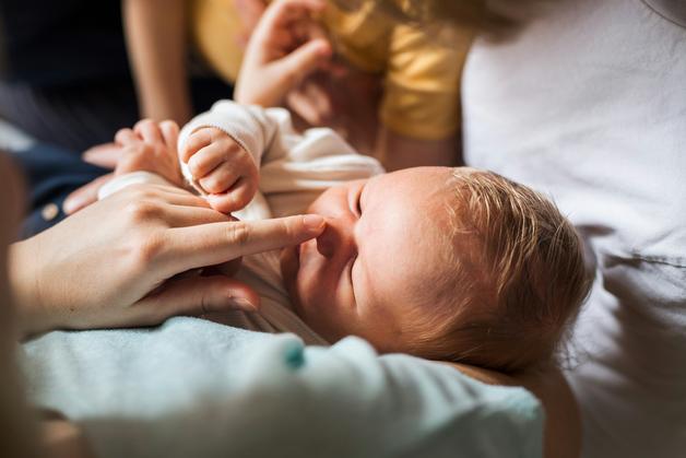 Un drp bébé adorable jouant avec une main, entouré de doux câlins familiaux.