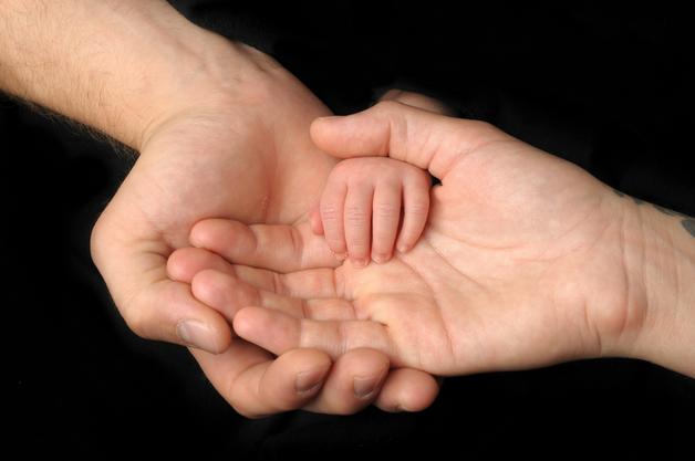 Mains d'adulte tenant une petite main d'enfant, symbolisant l'importance de la prévention de la maladie pied main bouche.