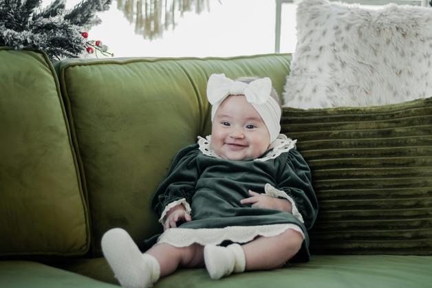 Bébé assis sur un canapé confortable, mettant en avant sa tenue mignonne et ses chaussettes adaptées à sa pointure bébé.