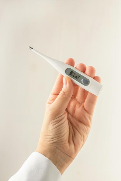 Thermomètre numérique dans une main, utilisé pour mesurer la température bébé.