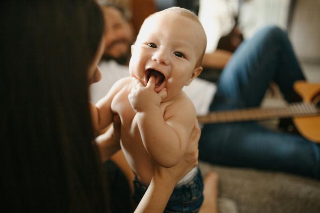 Un bébé souriant dans les bras de sa mère, potentiellement sujet à un vomissement en jet bébé.