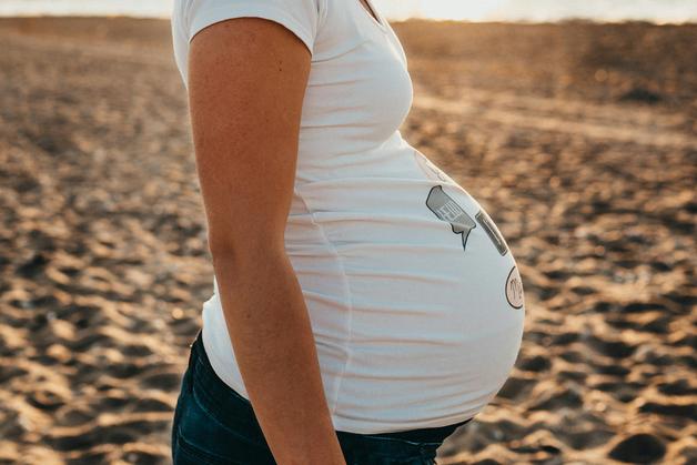 Femme enceinte sur la plage, illustrant la joie de la MAP grossesse et la beauté de la maternité.