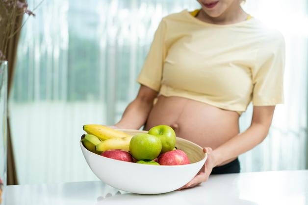 Femme enceinte face à un bol de fruits, symbolisant les choix alimentaires influencés par les aversions de grossesse