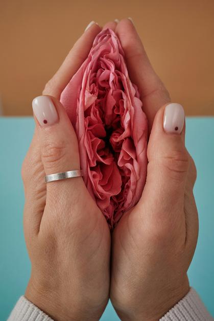 Mains tenant une fleur rose, symbolisant la douceur et l'épanouissement pendant la grossesse, en lien avec le bouchon muqueux grossesse.
