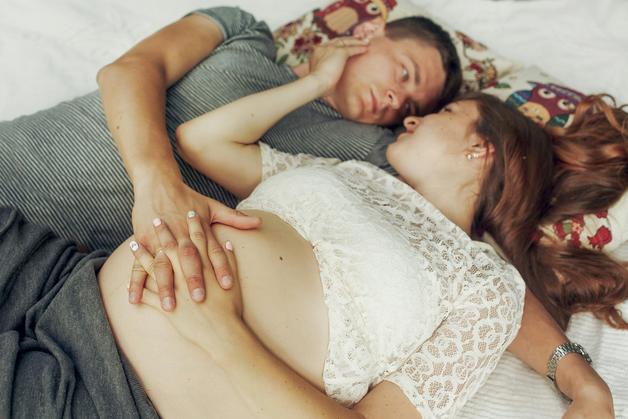 Couple allongé sur un lit, discutant du déclenchement d'accouchement et de l'arrivée imminente de leur bébé.