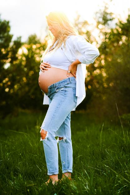 Femme enceinte dans un champ, exprimant l'attente d'une échographie du 1er trimestre.