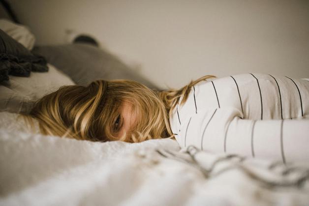 Femme allongée sur un lit, montrant des signes de fatigue grossesse avec une expression de lassitude.