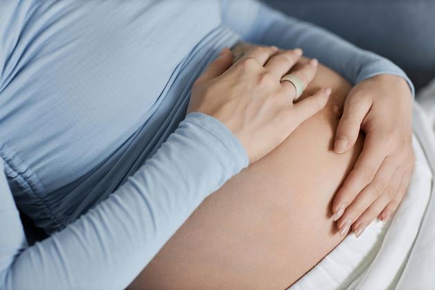 Ventre d’une femme enceinte en fin de grossesse, touché avec douceur, évoquant les sensations liées aux fausses contractions