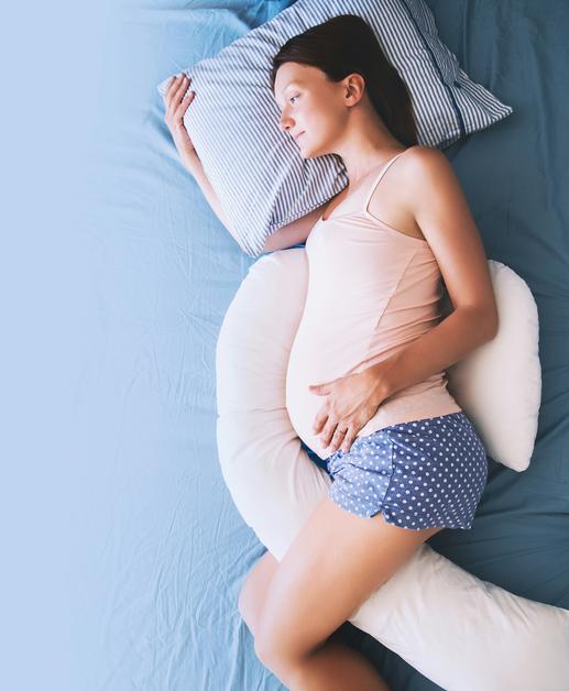 Femme enceinte se reposant sur un lit, illustrant les défis de l'insomnie enceinte.