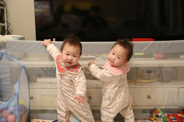 Des jumeaux fille garçon souriant, jouant ensemble dans leur chambre, entourés de jouets colorés.