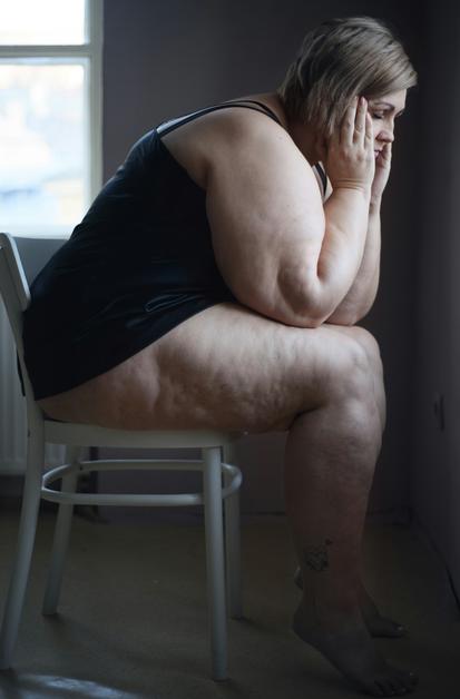 Femme enceinte assise sur une chaise, exprimant des maux de tête enceinte, visiblement préoccupée et fatiguée.