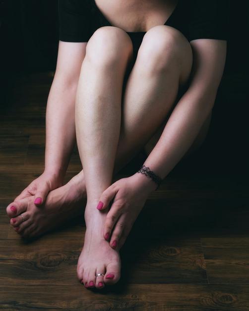 Femme assise tenant ses pieds, illustrant des pieds gonflés enceinte, une condition courante durant la grossesse.