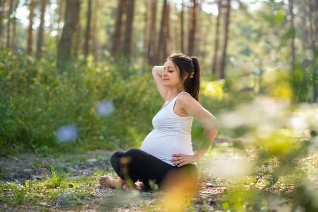 Femme enceinte assise dans un parc, montrant des signes de confort malgré ses pieds gonflés enceinte.