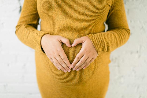 Femme enceinte formant un cœur sur son ventre, symbole de santé pendant la grossesse, en lien avec la protéinurie grossesse.