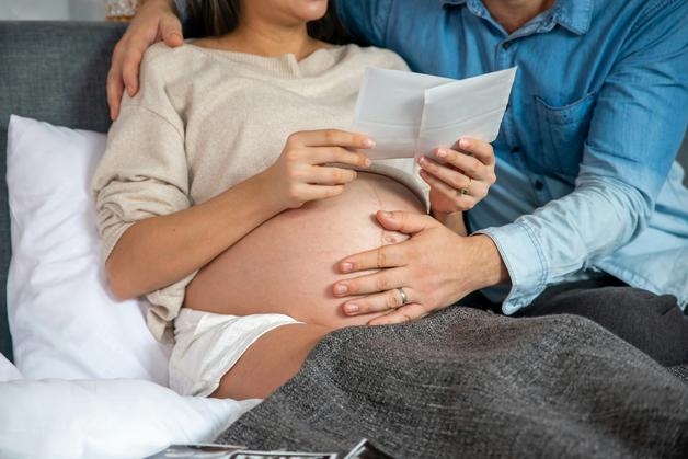 Couple regardant des documents, l'un en train de reconnaître contractions pendant la grossesse.