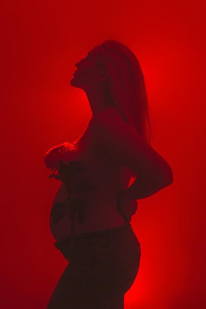 Femme enceinte en silhouette, se tenant le dos, illustrant la douleur de la sciatique enceinte.