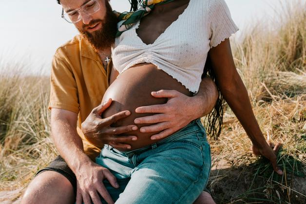 Un couple souriant s'embrasse tendrement, explorant la sexualité grossesse et la connexion entre eux pendant la grossesse.