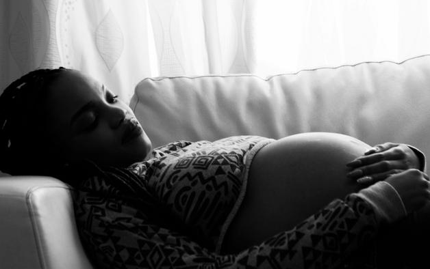Femme enceinte observant des signes d'accouchement imminent, allongée sur un canapé.
