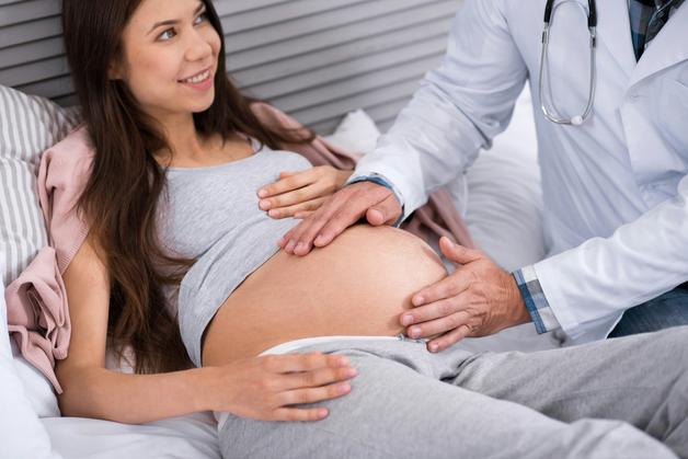 Contrôle médical de grossesse, signes accouchement imminent détectés par le médecin sur le ventre de la femme enceinte.