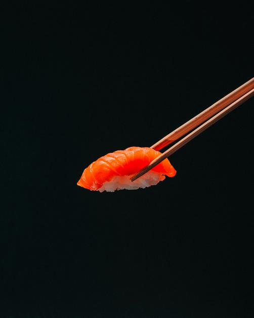 Sushi délicat tenu avec des baguettes, idéal à éviter pendant la grossesse, sushis enceinte.
