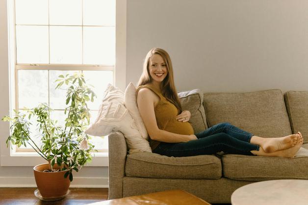 Femme enceinte assise sur un canapé, mettant en avant la symphyse pubienne et le bien-être durant la grossesse.