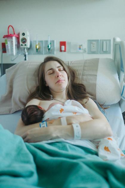Jeune mère allongée dans un lit d’hôpital tenant son bébé en peau à peau après un accouchement par ventouse