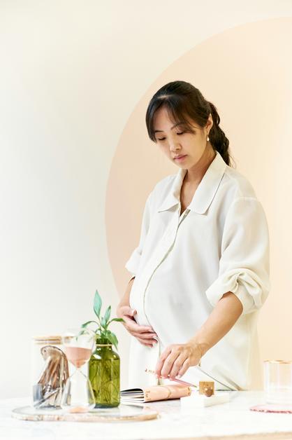 Femme enceinte caressant son ventre dur enceinte tout en consultant un livre sur la grossesse.