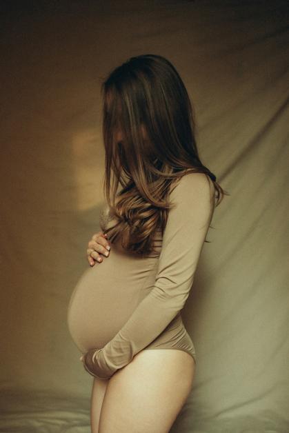Femme enceinte se tenant le ventre, ressentant un ventre qui gratte enceinte, dans une ambiance douce et apaisante.