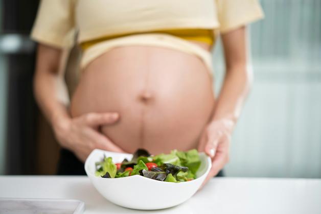 Femme enceinte tenant un saladier, soulignant l'importance d'éviter les aliments interdits enceinte.