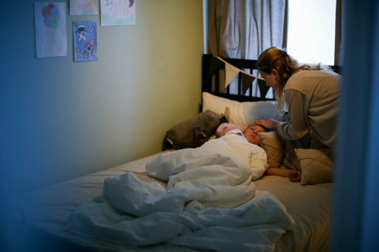 Maman touche le front d'un enfant malade de la grippe allongé dans son lit